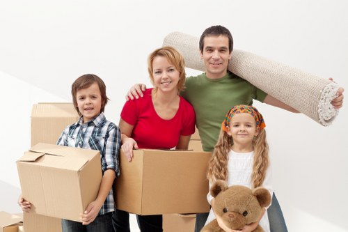Movers carrying furniture down a narrow staircase in Queens Park